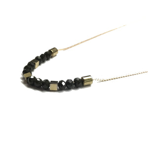 Gold brass tube bead with black faceted glass beads and gold square hematite bead spacers on a thread necklace
